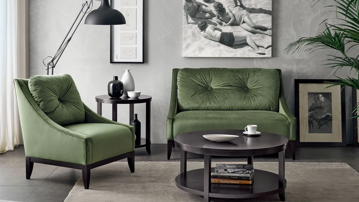 Classic contemporary small living room in a traditional American style. 2-Seater sofa and armchair in green velvet combined with round wooden coffee table and matching lamp table