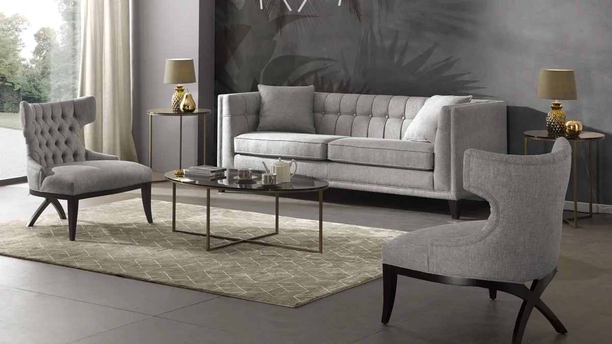 Classic contemporary  living room in a traditional American style. 3-Seater Lixis sofa in grey boucl fabric, combined with tufted back armchairs and round metal base, glass top, oval coffee table and small lamp tables