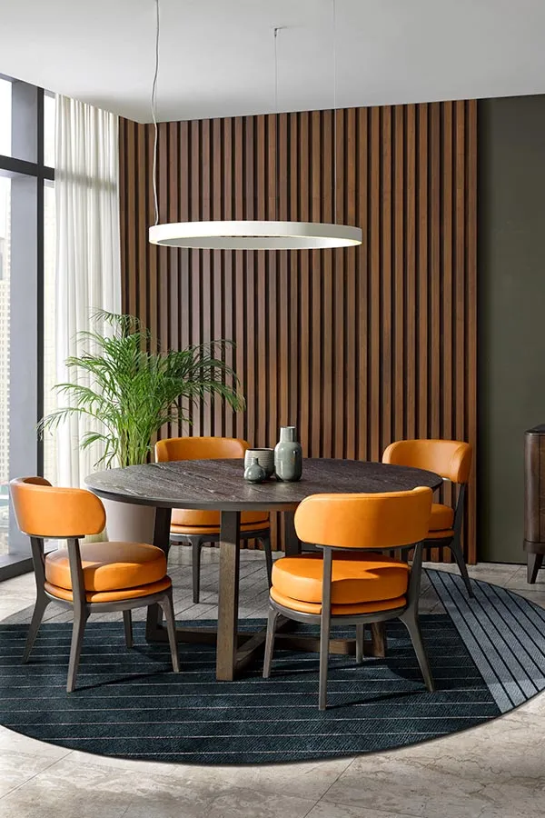 Zona dining moderna composta dal tavolo rotondo Caspio e da quattro sedie Alide dalle linee moderne e rivestite in pelle arancio. Collezione Ada by Sevensedie