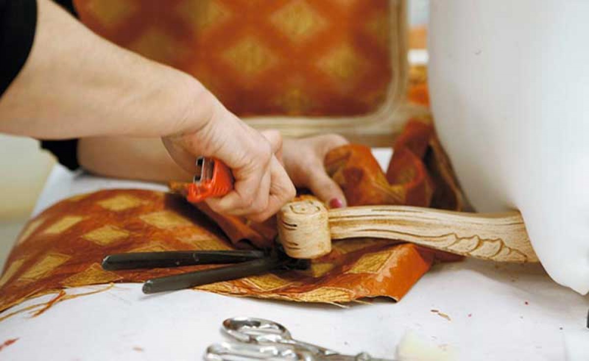 A skilful upholsterer hand-fixing fabric to the chair’s armrest at Sevensedie in Italy