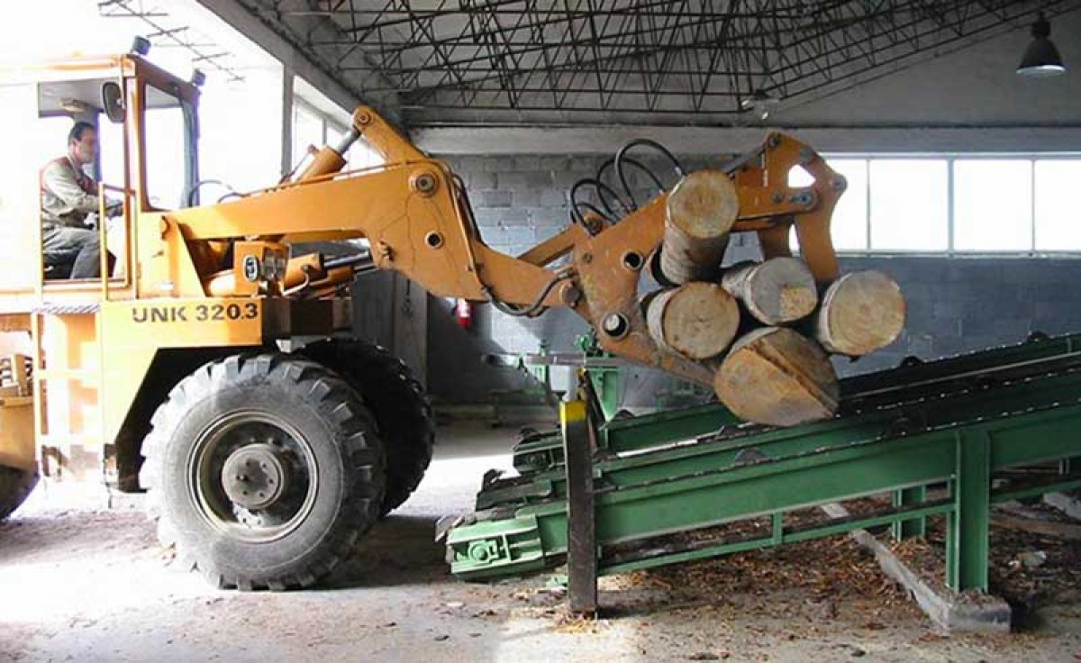 bulldozer transporting wood logs used to manufacture furniture at Sevensedie in Italy