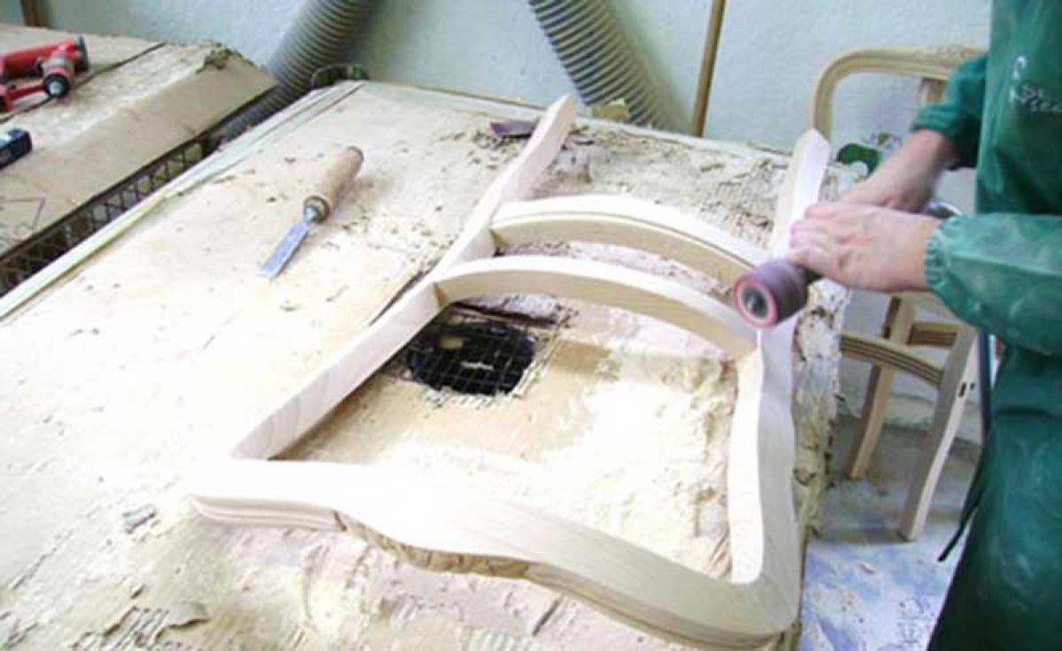 Italian manufacturer sanding the backrest of a wooden chair at Sevensedie