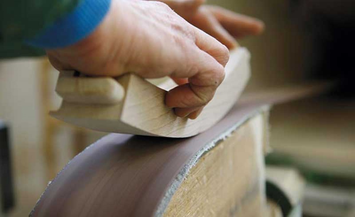 Italian manufacturer sanding the seat side rail of a wooden chair at Sevensedie