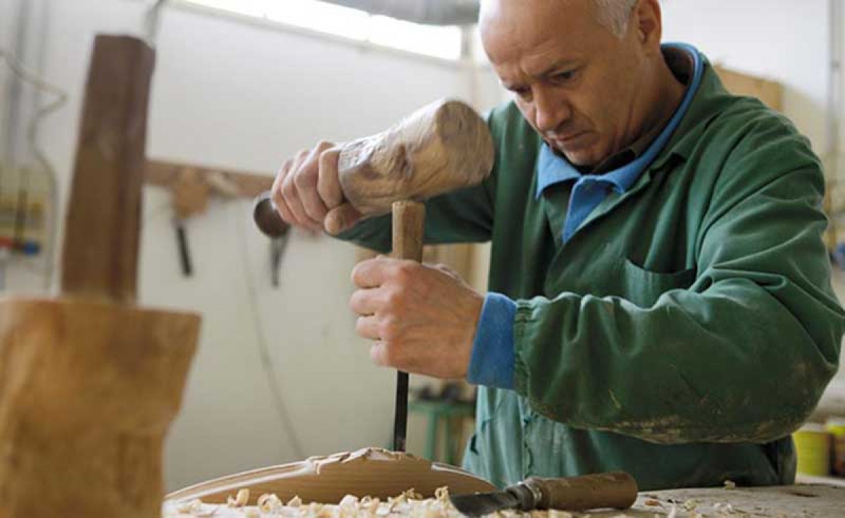 Operator hand-carves a chair at Sevensedie in Italy