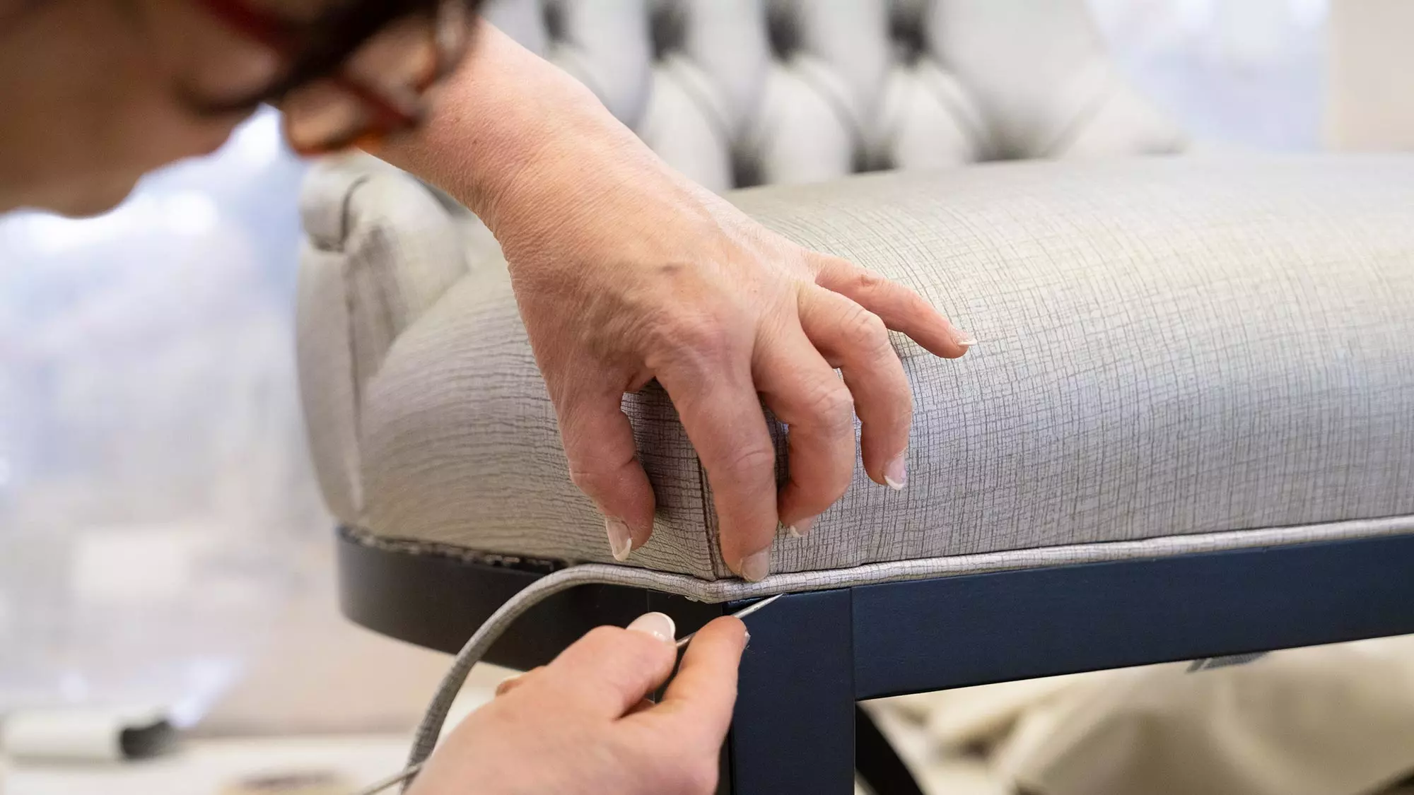A skilful upholsterer hand-fixing fabric to the chair?s armrest at Sevensedie in Italy