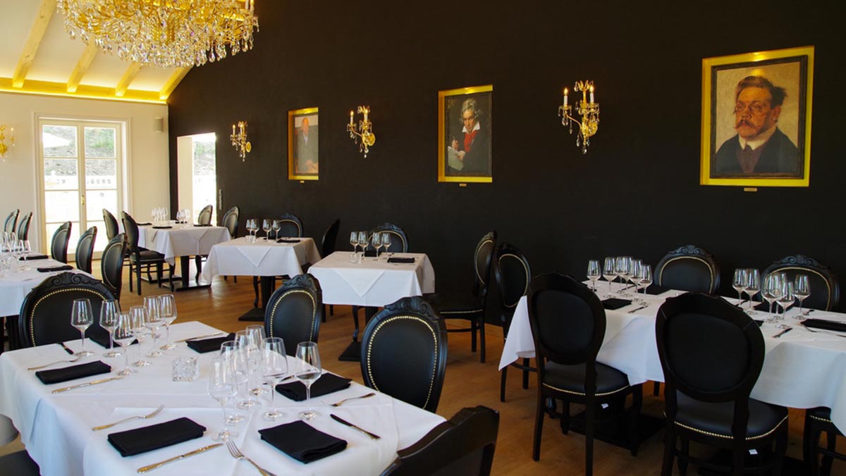 General view of the dining area at the Ludwig restaurant. Classic Louis Style dining chairs Sabry in dull black finish, with ?U? stretcher and upholstered in black Vinyl. Contemporary square Atene dining tables on pillar pedestals lacquered in a dull black finish.