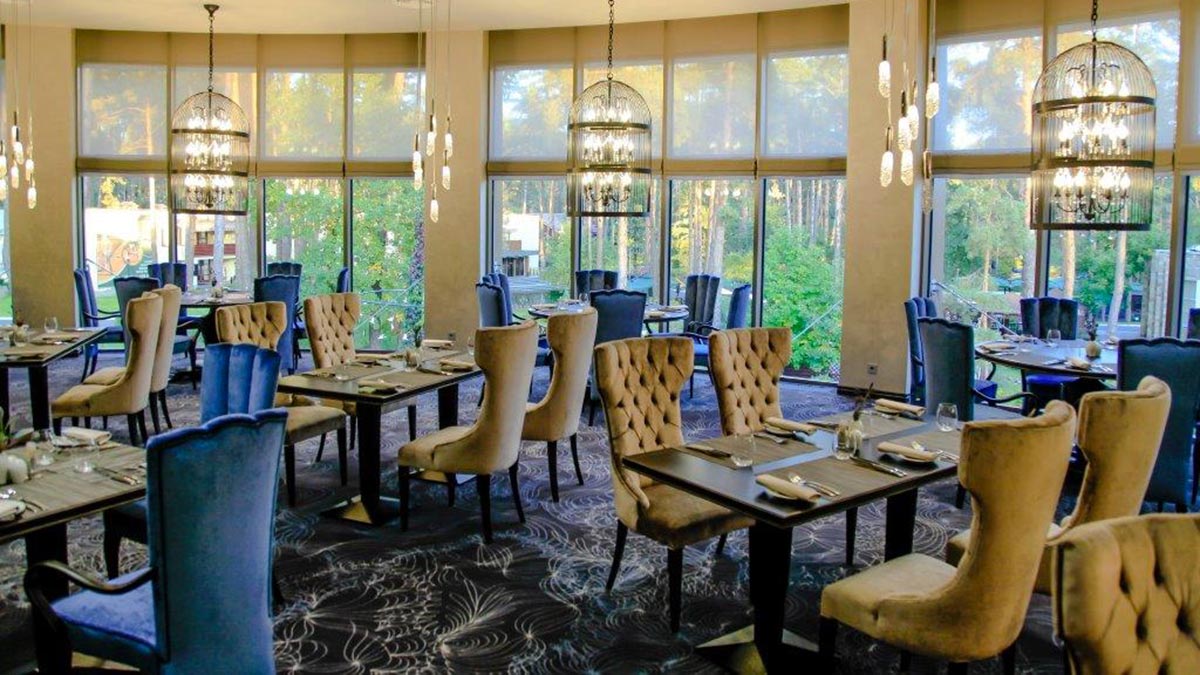 general view of the dining area of the Mozart restaurant looking out into the forest. 10 contemporary high back Queen dining chair, 10 square Atene dining tables ad a few large Bisotus round table. Hi quality Italian furniture by Sevensedie, 100% made in Italy