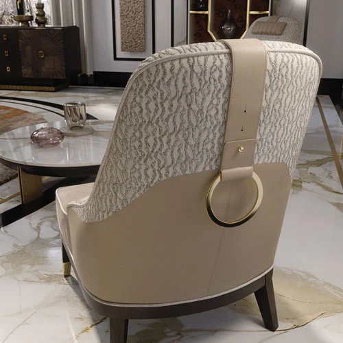 Un primo piano dello schienale della poltrona, caratterizzato da un inserto in pelle beige con un anello ornamentale placcato oro
